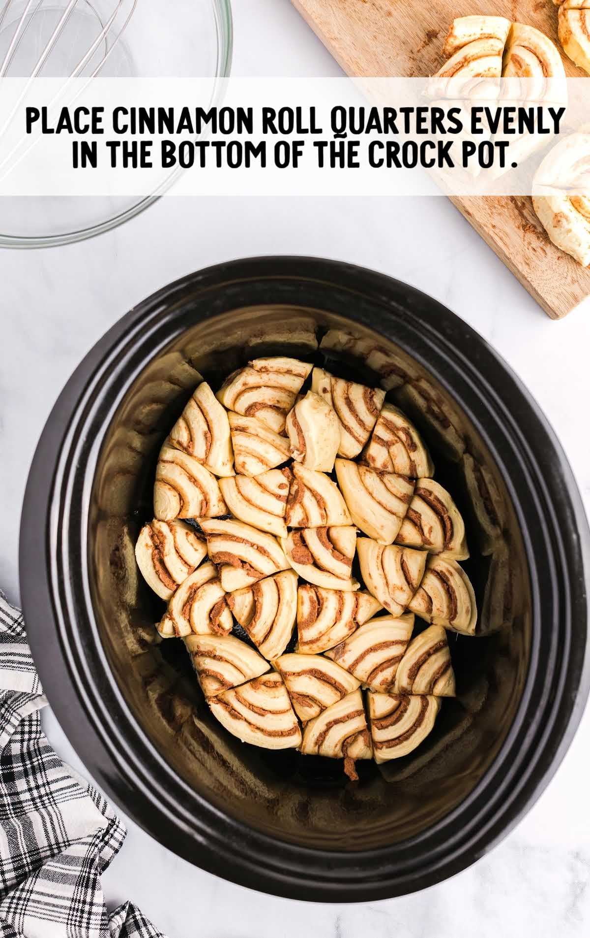 cinnamon roll quarters placed in the bottom of a crockpot
