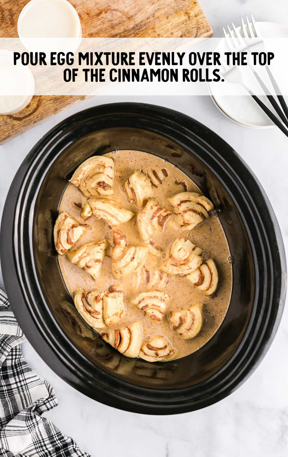 egg mixture poured over the cinnamon rolls in a crockpot