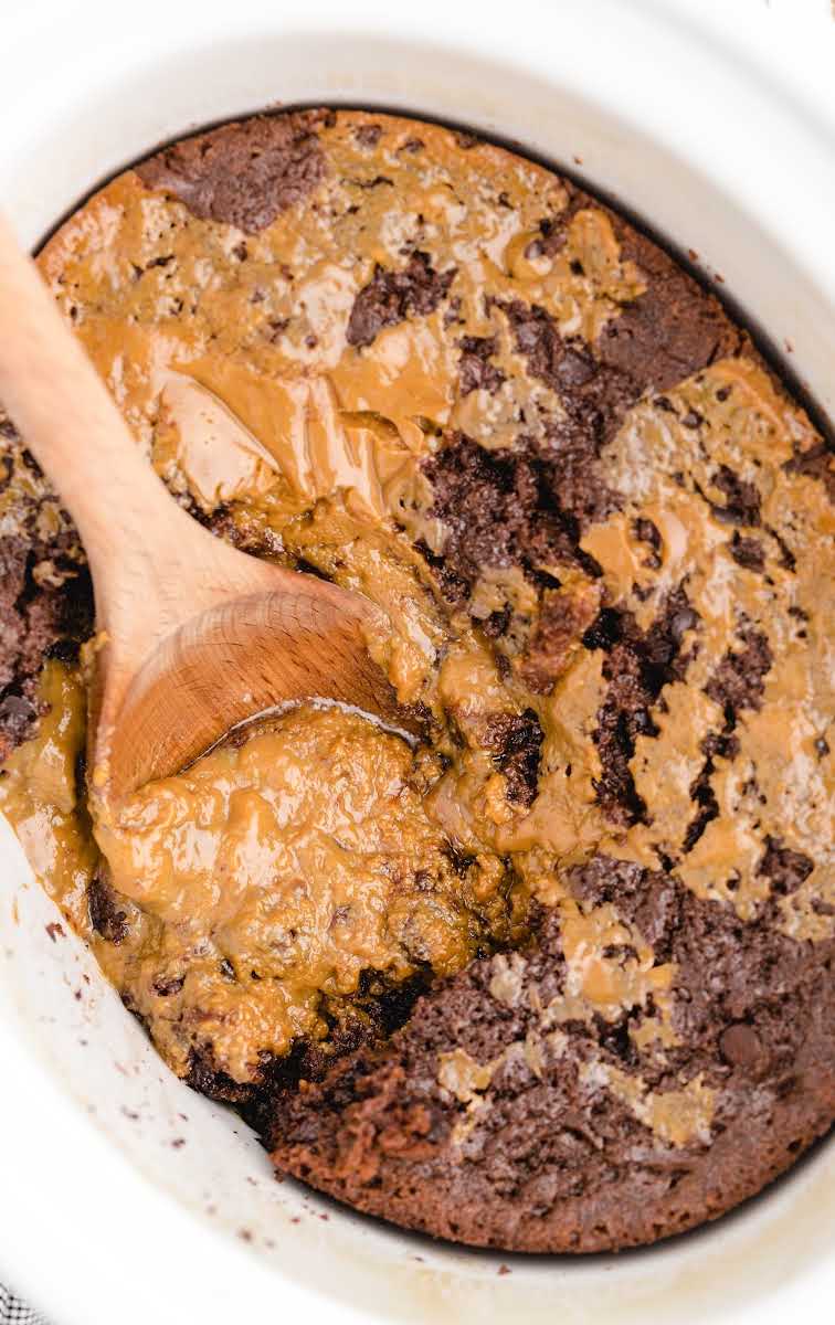 close up overhead shot of Crockpot Chocolate Caramel Cake in a crockpot with a large wooden spoon