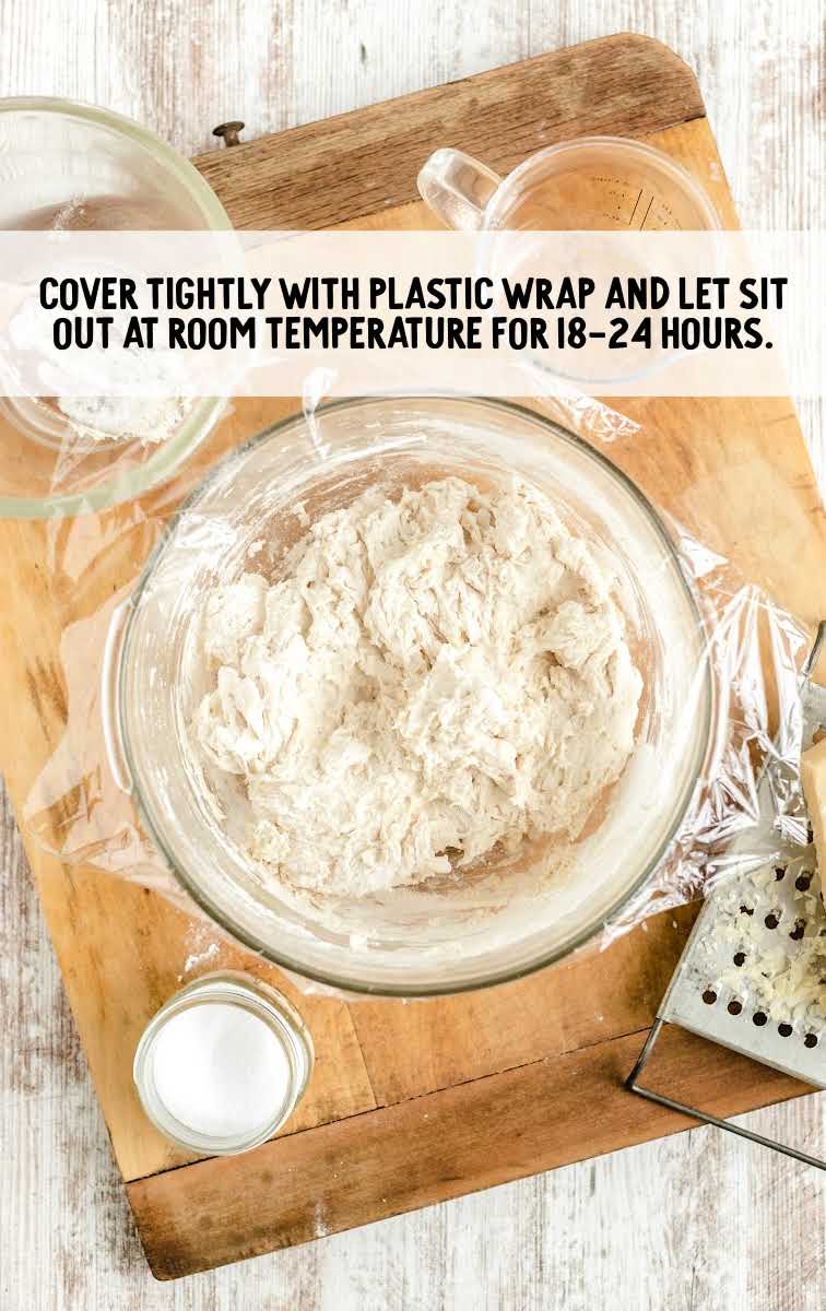 plastic wrap placed on top of a bowl of bread dough
