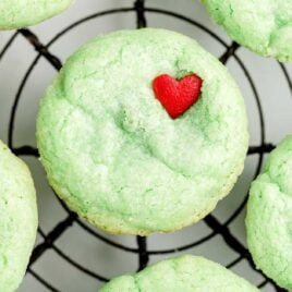 close up overhead shot of Grinch Stuffed Cookies topped with a heart candy sprinkle on a cooling rack