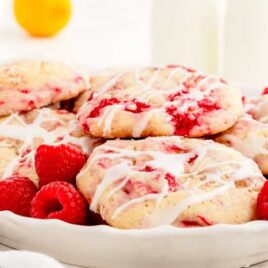close up shot of Lemon Raspberry Cookies garnished with lemon glaze and piled in a bowl with raspberries