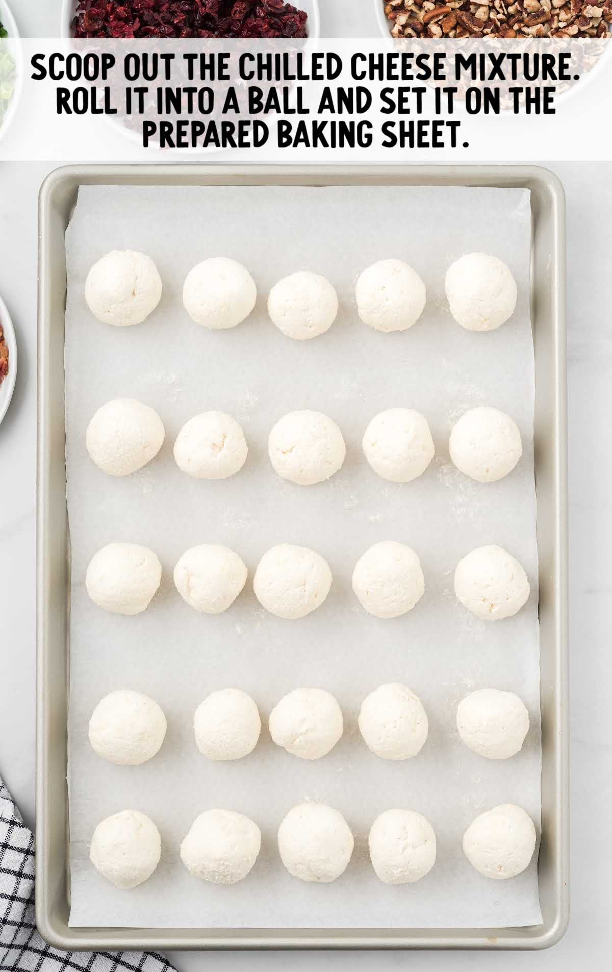 Uncoated cheeseball mixture rolled into balls and arranged on a parchment-lined baking sheet.