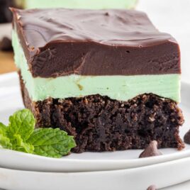 close up shot of a slice of Mint Chocolate Brownies with a mint leaf on a plate