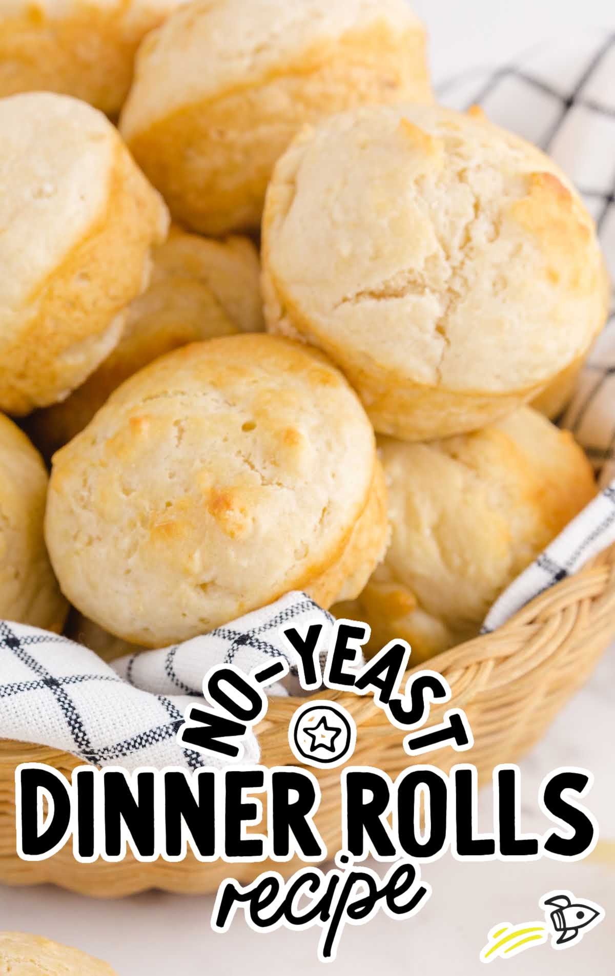 Close-up of golden, fluffy no yeast dinner rolls in a wicker basket lined with a checkered cloth.