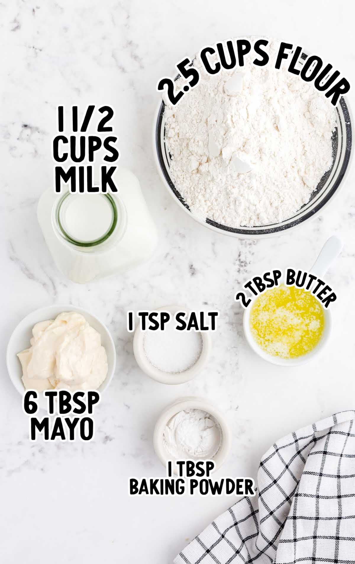 Overhead view of labeled ingredients for no yeast dinner rolls, including flour, milk, mayo, butter, salt, and baking powder.