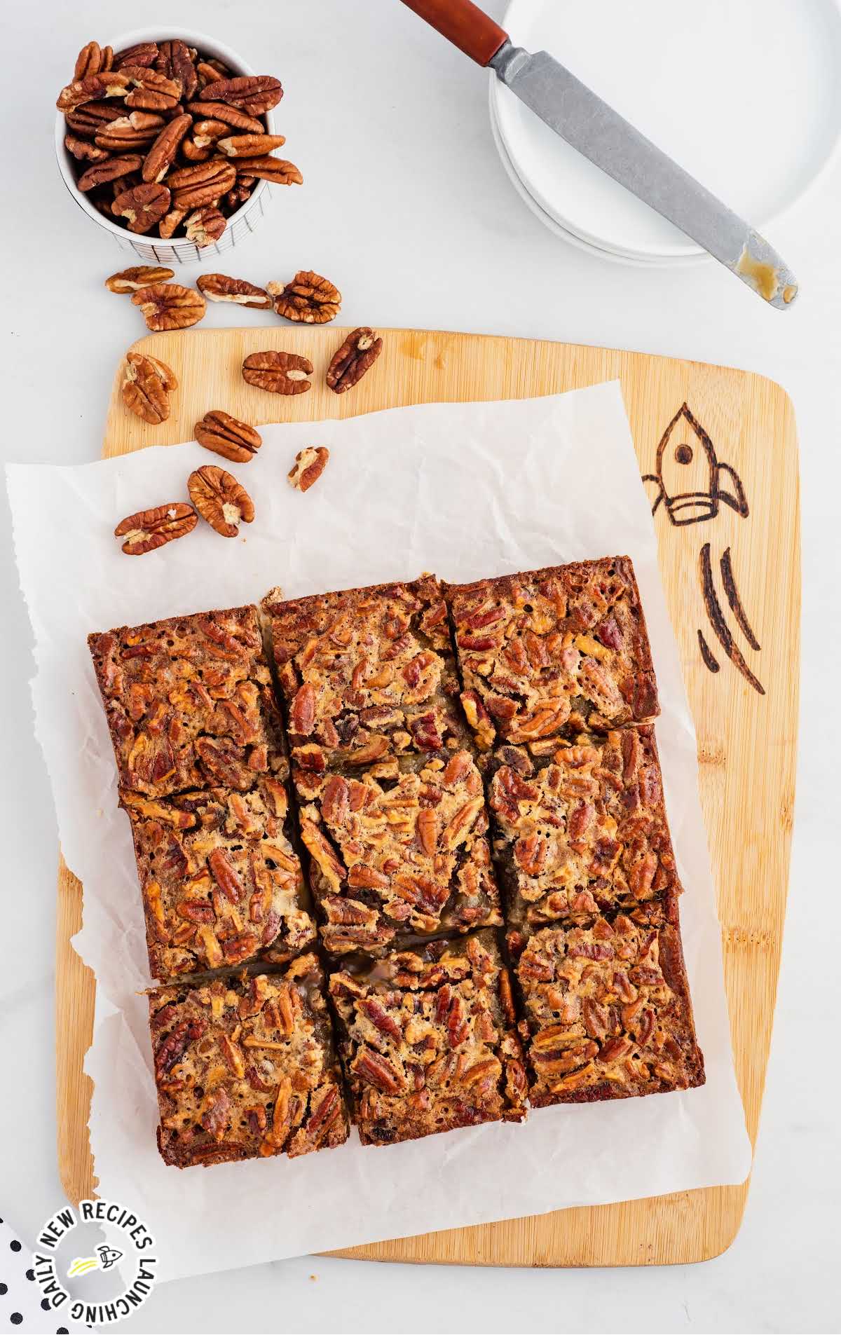 overhead shot of Pecan Pie Bars on a wooden board with a bowl of pecans