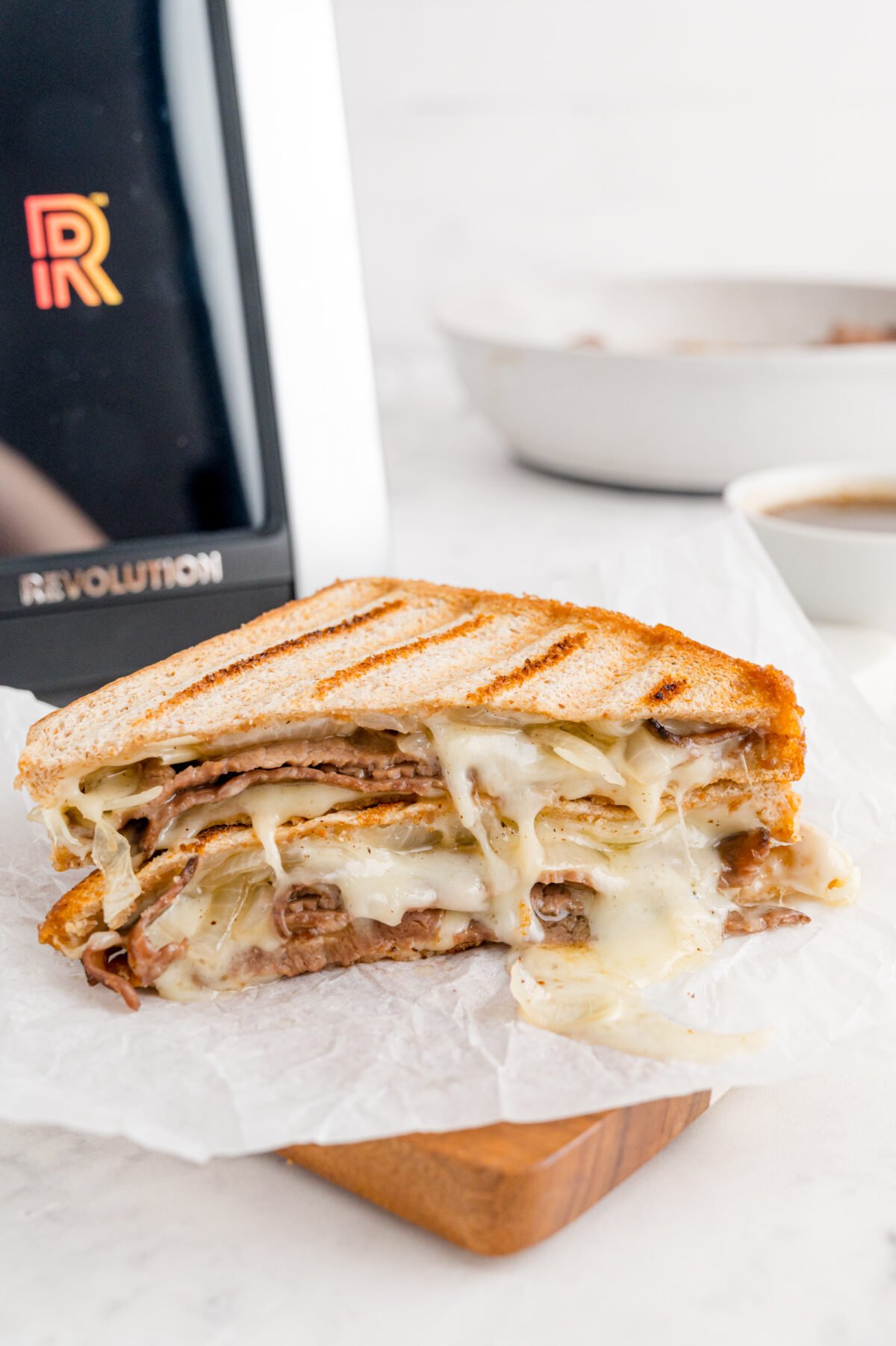 close up shot of roast beef panini with au jus cut in half and stacked on top of each other