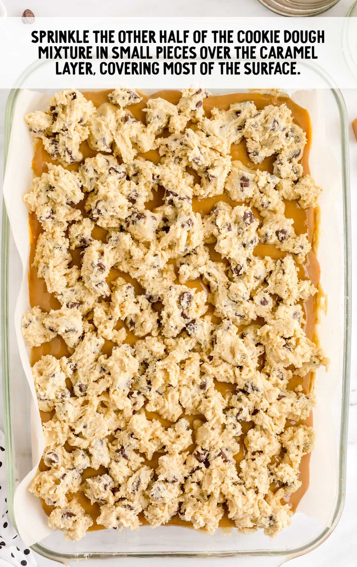 cookie dough being sprinkled on top of the caramel layer