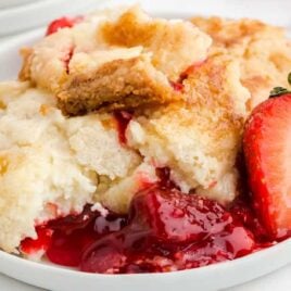 close up shot of a serving of Strawberry Dump Cake with slices of strawberry on a plate