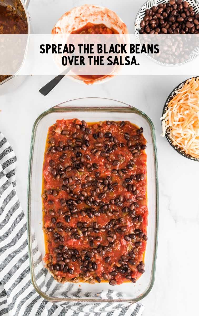Taco Lasagna process shot of black beans spread on top of salsa