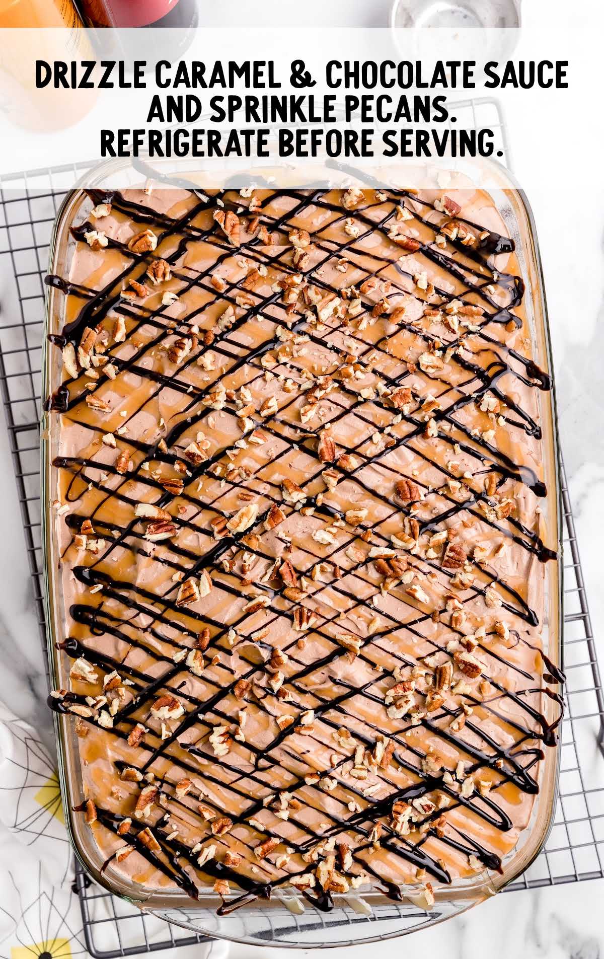cake drizzled with caramel and chocolate sauce then sprinkled with pecans