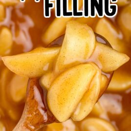 close up overhead shot of apple pie filling on a spoon that is hovered over a pan of apple pie filling