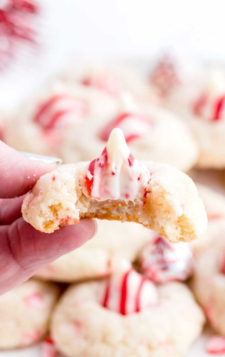 close up shot of candy cane kiss cookies being held with a bite taken out of it