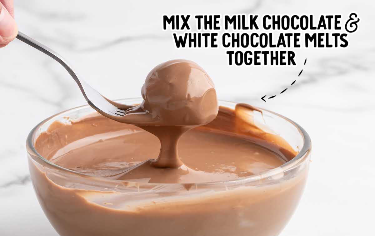 Coconut ball being dipped into a smooth mixture of melted milk and white chocolate.