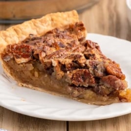 Close-up slice of pecan pie showing flaky crust and nutty filling.