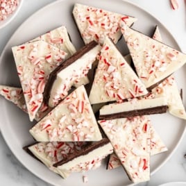 Plate of peppermint bark triangles made with layers of dark and white chocolate topped with crushed candy canes