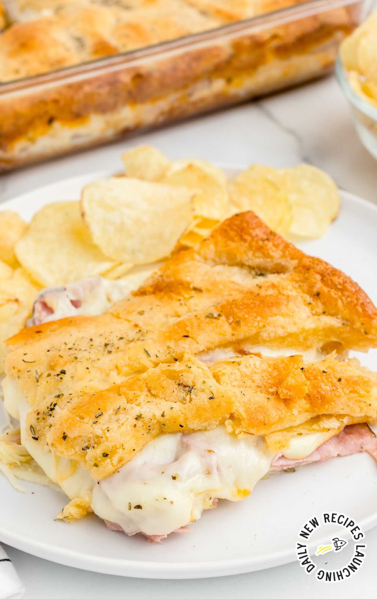 close up shot of a plate of Baked Ham and Cheese Sandwiches served with chips