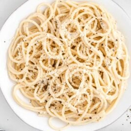 close up shot of a bowl of Cacio e Pepe topped with parmesan cheese