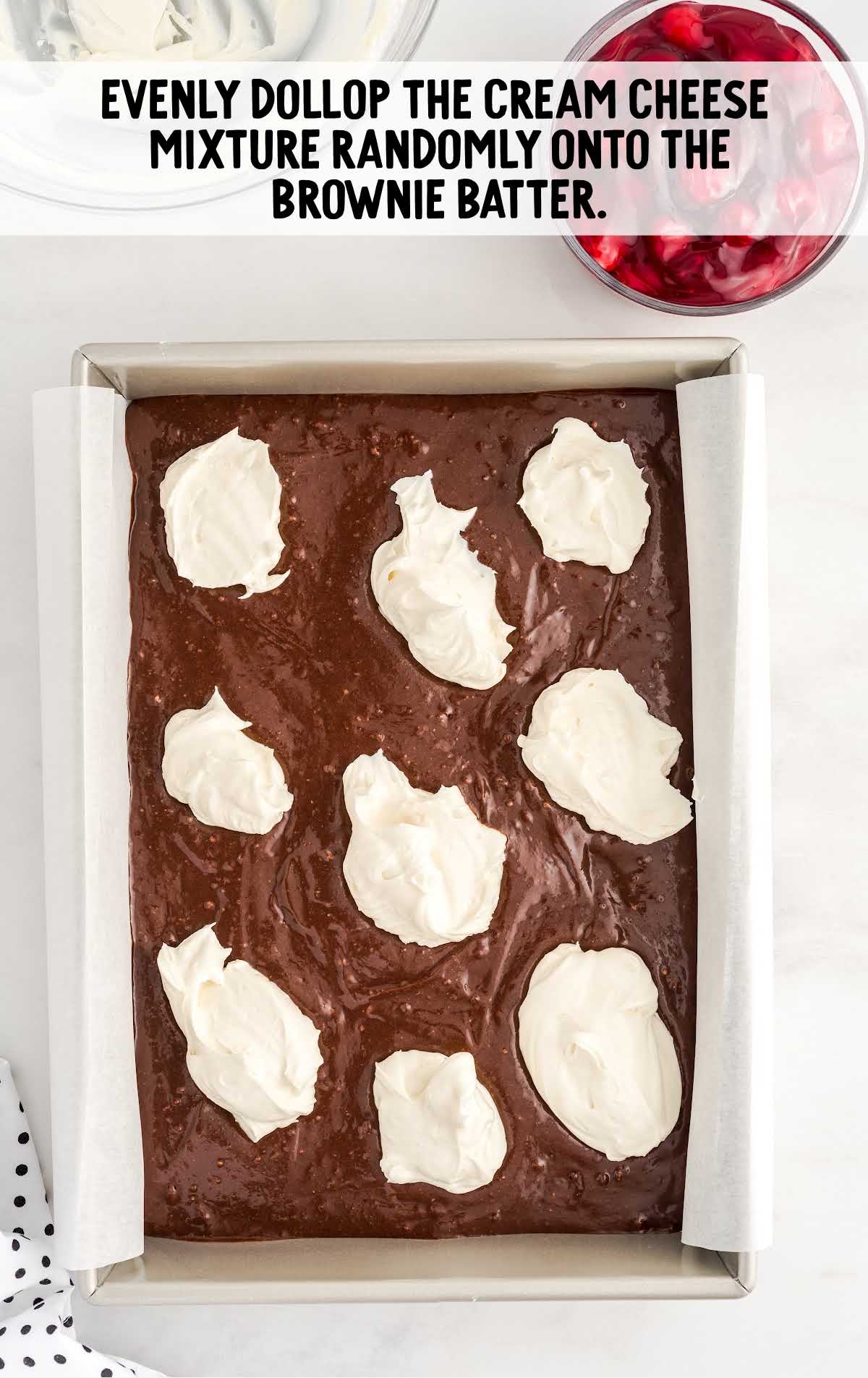 scoops of cream cheese mixture placed on top of the brownie mixture