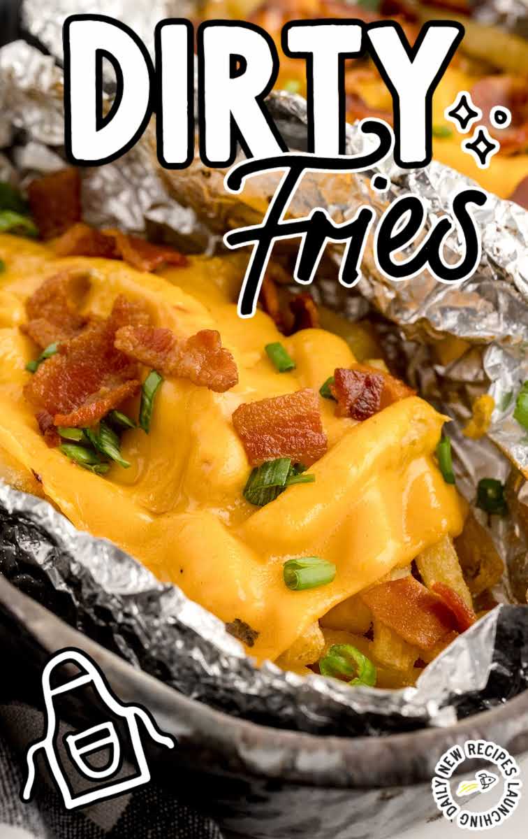 close up shot of a aluminum foil of Dirty Fries topped with cheese then garnished with bacon bits and green onions