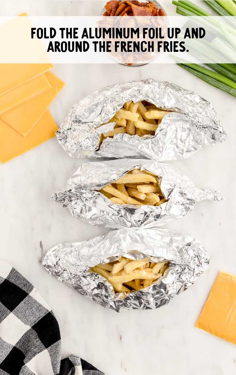 Dirty Fries process shot of French fries wrapped in sheets of aluminum foil