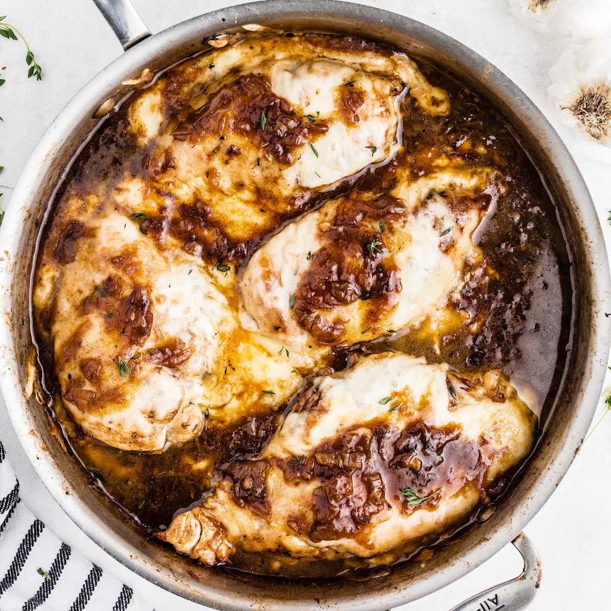 close up overhead shot of a skillet of French onion chicken garnished with thyme