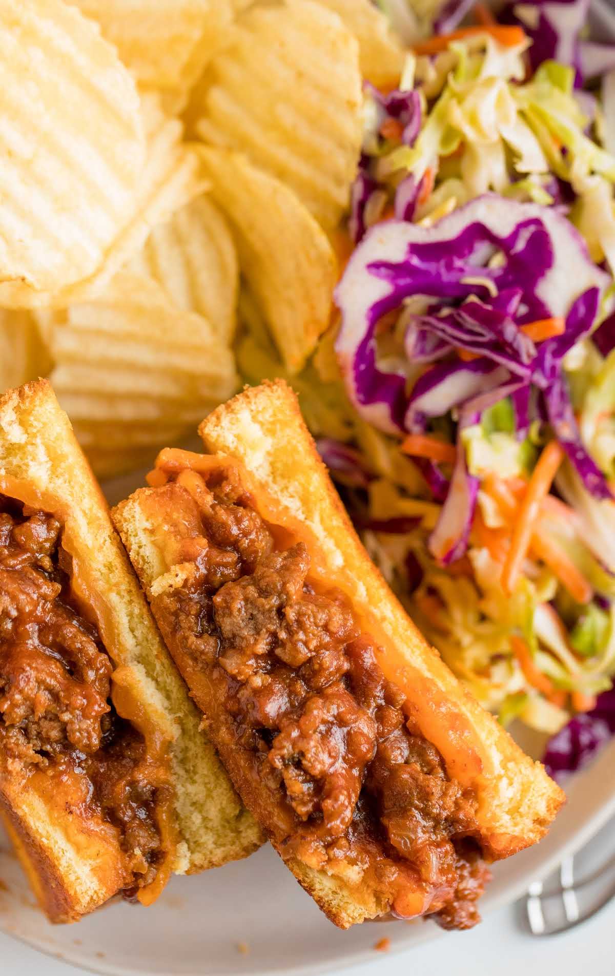 close up overhead shot of Grilled Cheese Sloppy Joes served with chips and coleslaw on a plate