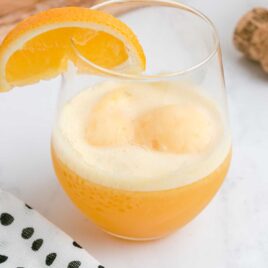 close up shot of a glass of Mimosa Float garnished with a orange slice