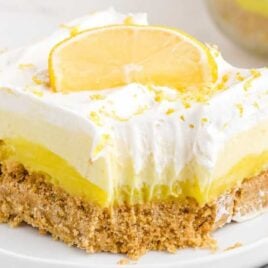 close up shot of a slice of No-Bake Lemon Pie garnished with lemon peel and a slice of lemon on a plate