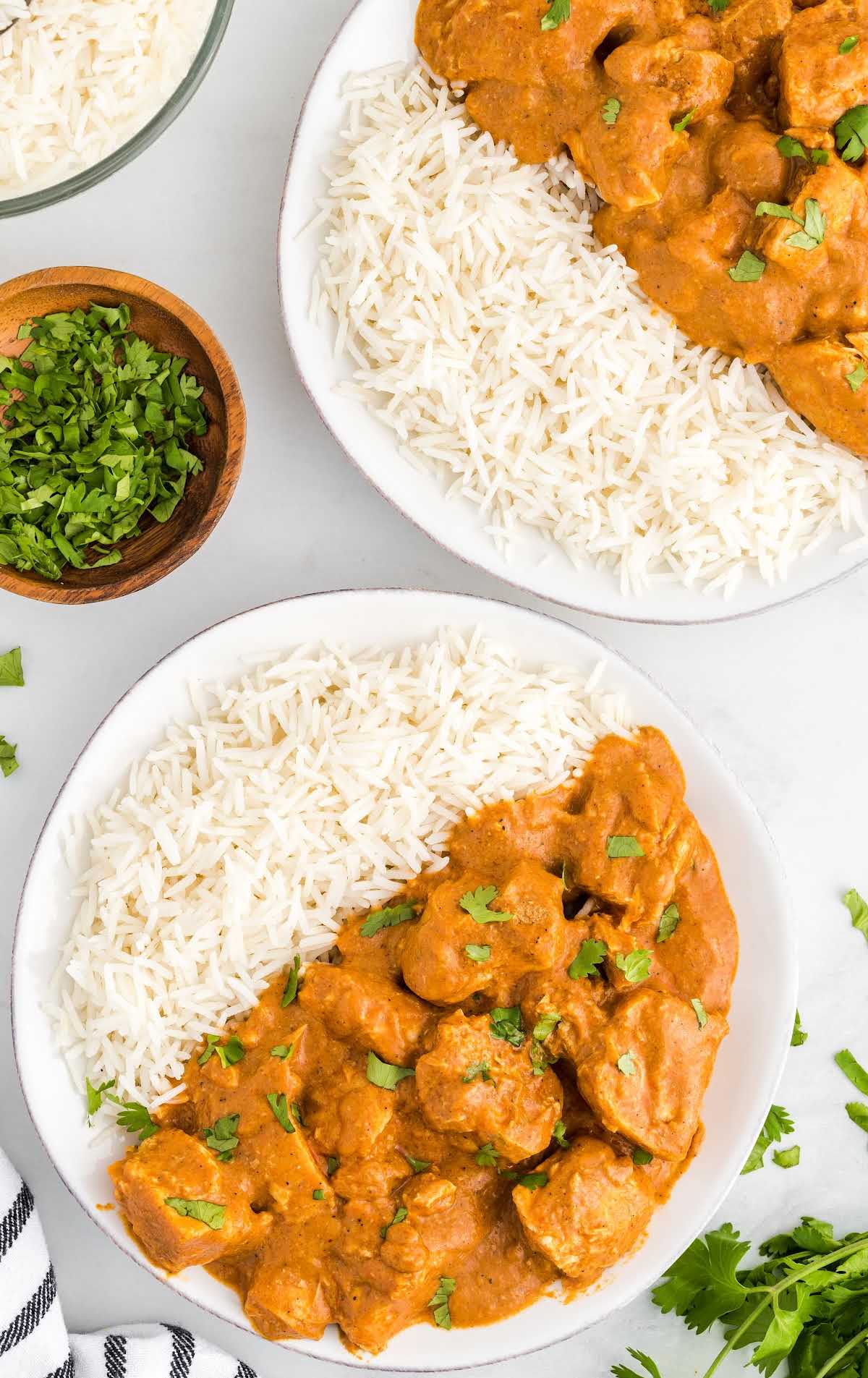 close up overhead shot of bowls of slow cooker butter chicken garnished with cilantro and served with jasmine rice