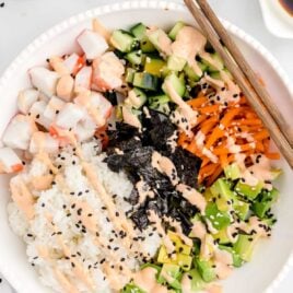 close up overhead shot of a bowl of Sushi Bowl garnished with sriracha mayonnaise with chopsticks