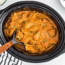 close up overhead shot of slow cooker butter chicken garnished with cilantro in a slow cooker