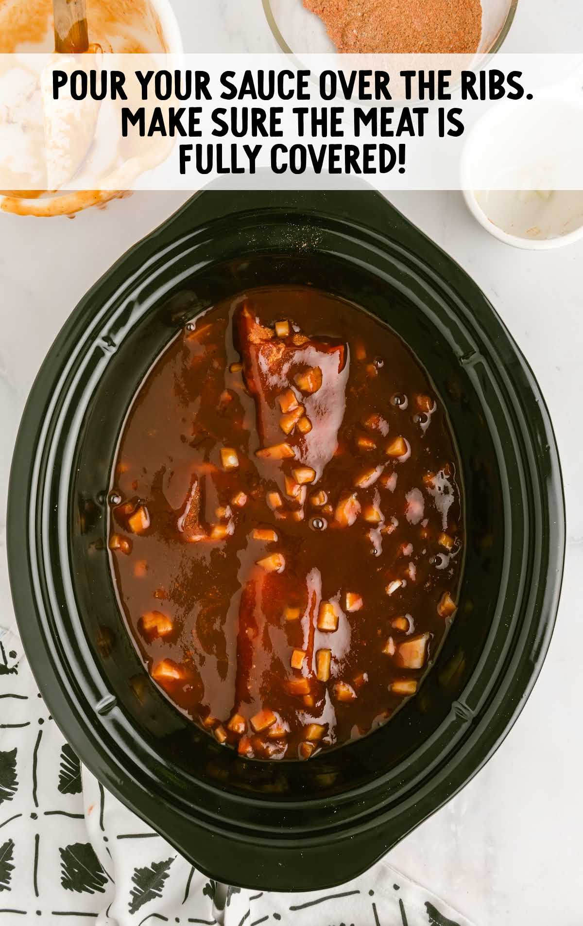 sauce poured over the ribs in a slow cooker