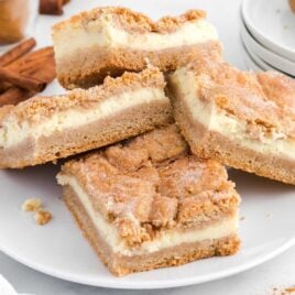 close up shot of snickerdoodle cheesecake bars piled on a plate