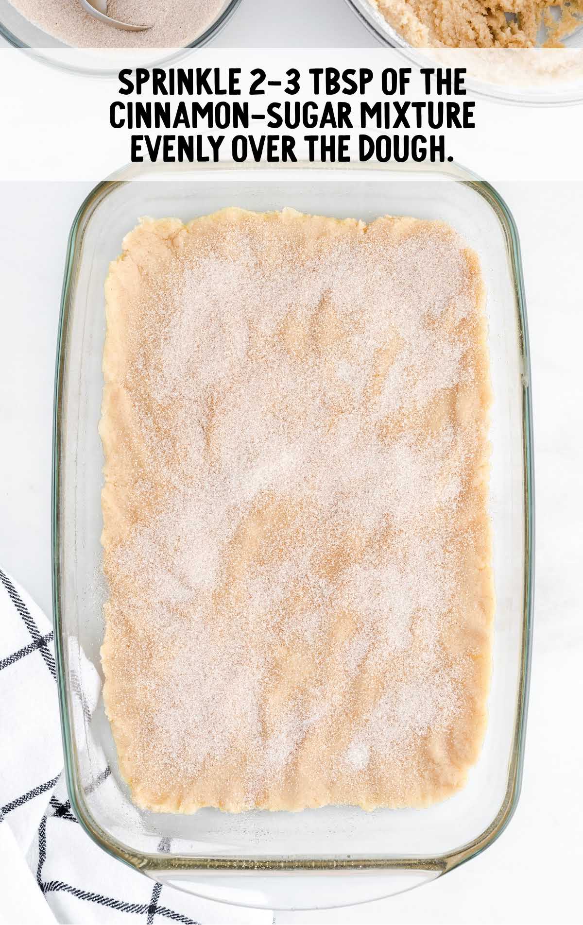 cinnamon sugar mixture sprinkled on top of the dough mixture in the baking dish