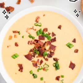 close up overhead shot of a bowl of Beer Cheese Soup topped with bacon bits and green onions