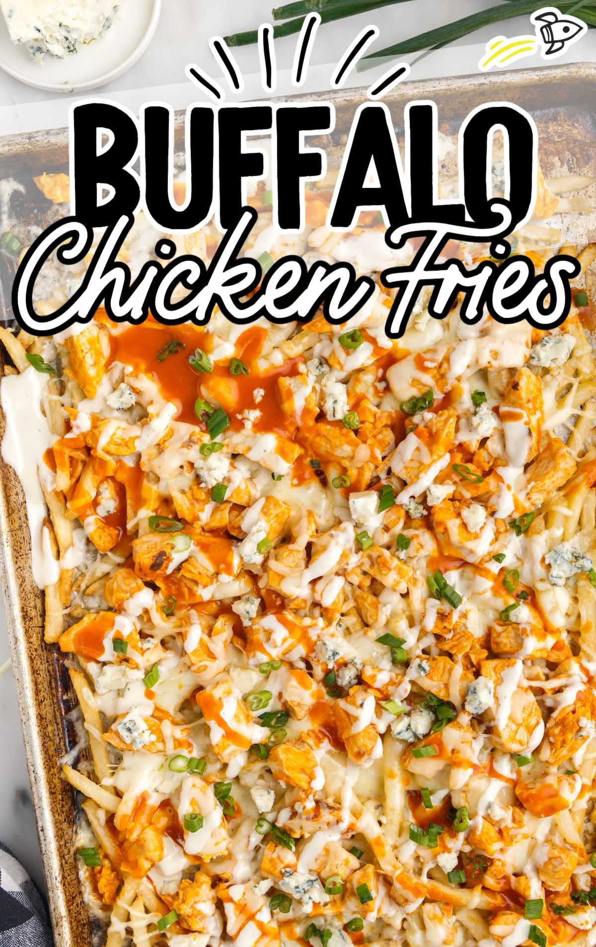 close up overhead shot of a sheet pan of Buffalo Chicken Fries topped with buffalo sauce and ranch then garnished with green onions