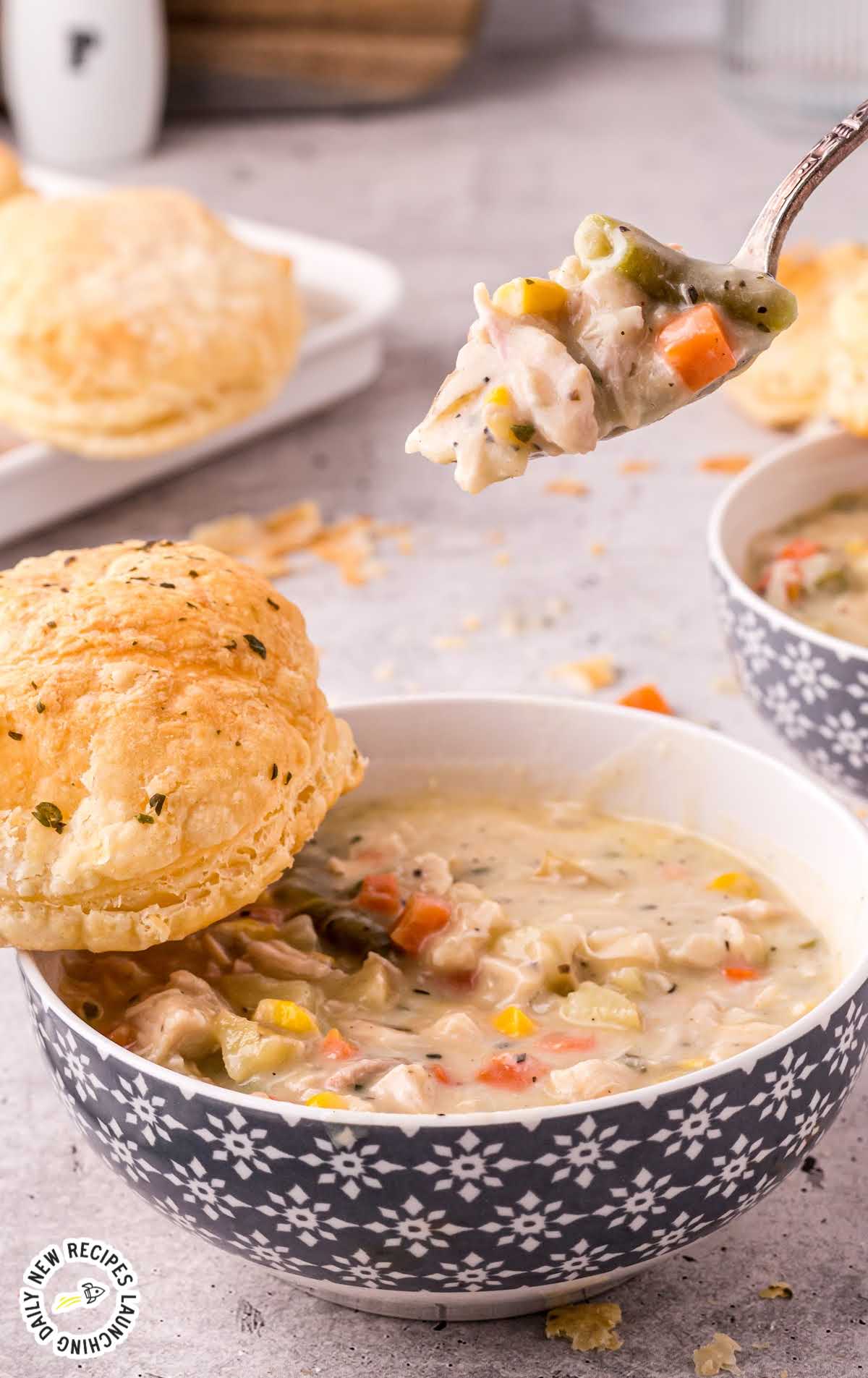 close up shot of a bowl of Chicken Pot Pie Soup with a piece of bread