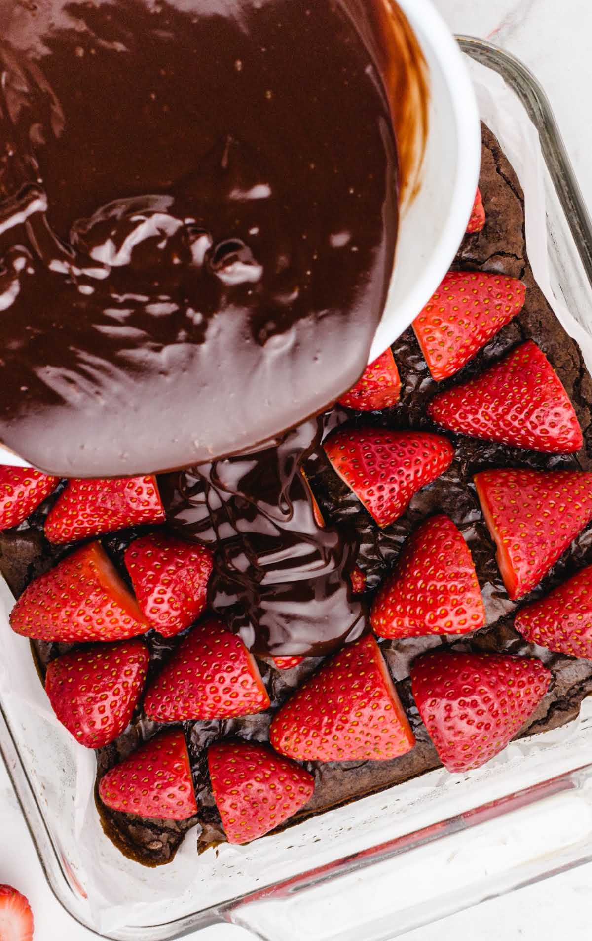 close up shot of chocolate ganache being poured onto the strawberries for Chocolate Covered Strawberry Brownies