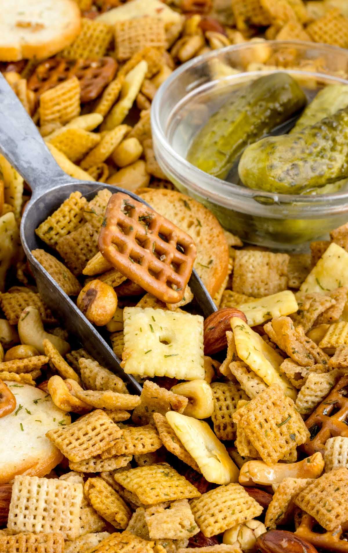 close up shot of a bunch of Dill Pickle Chex Mix and a small dish of dill pickles