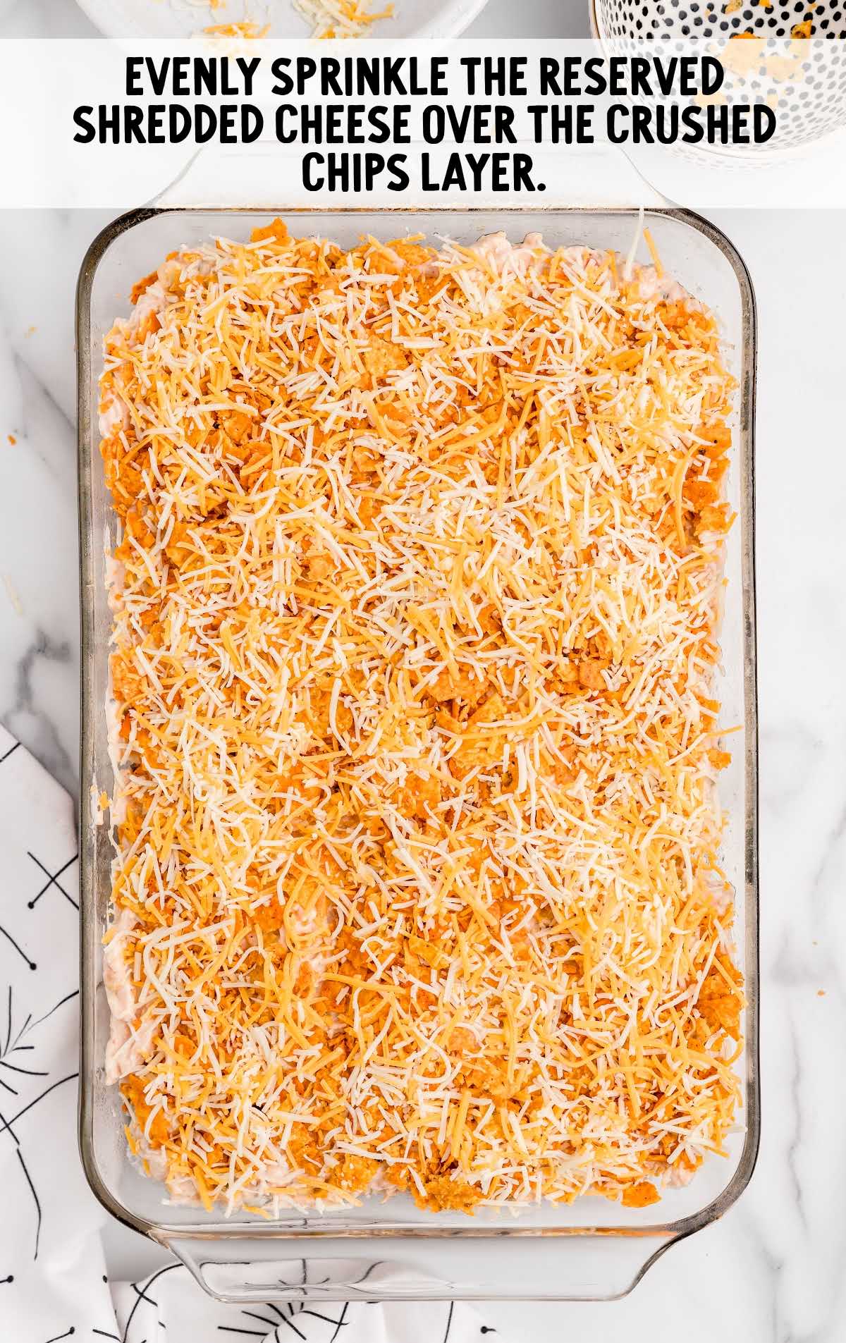 Doritos Cheesy Chicken Casserole process shot of shredded cheese sprinkled on top of the crushed Doritos