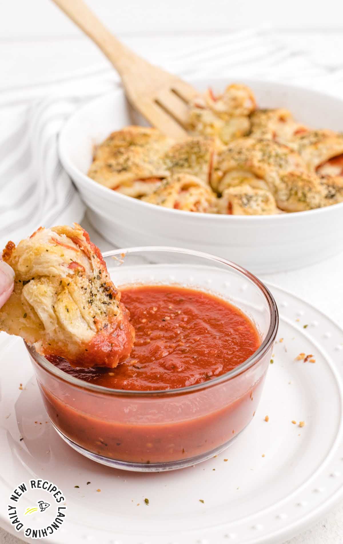 close up shot of Easy Pepperoni Rolls being dipped into a bowl of marinara sauce