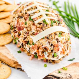 close up shot of Football Cheese Ball garnished with green onions and served with ritz crackers