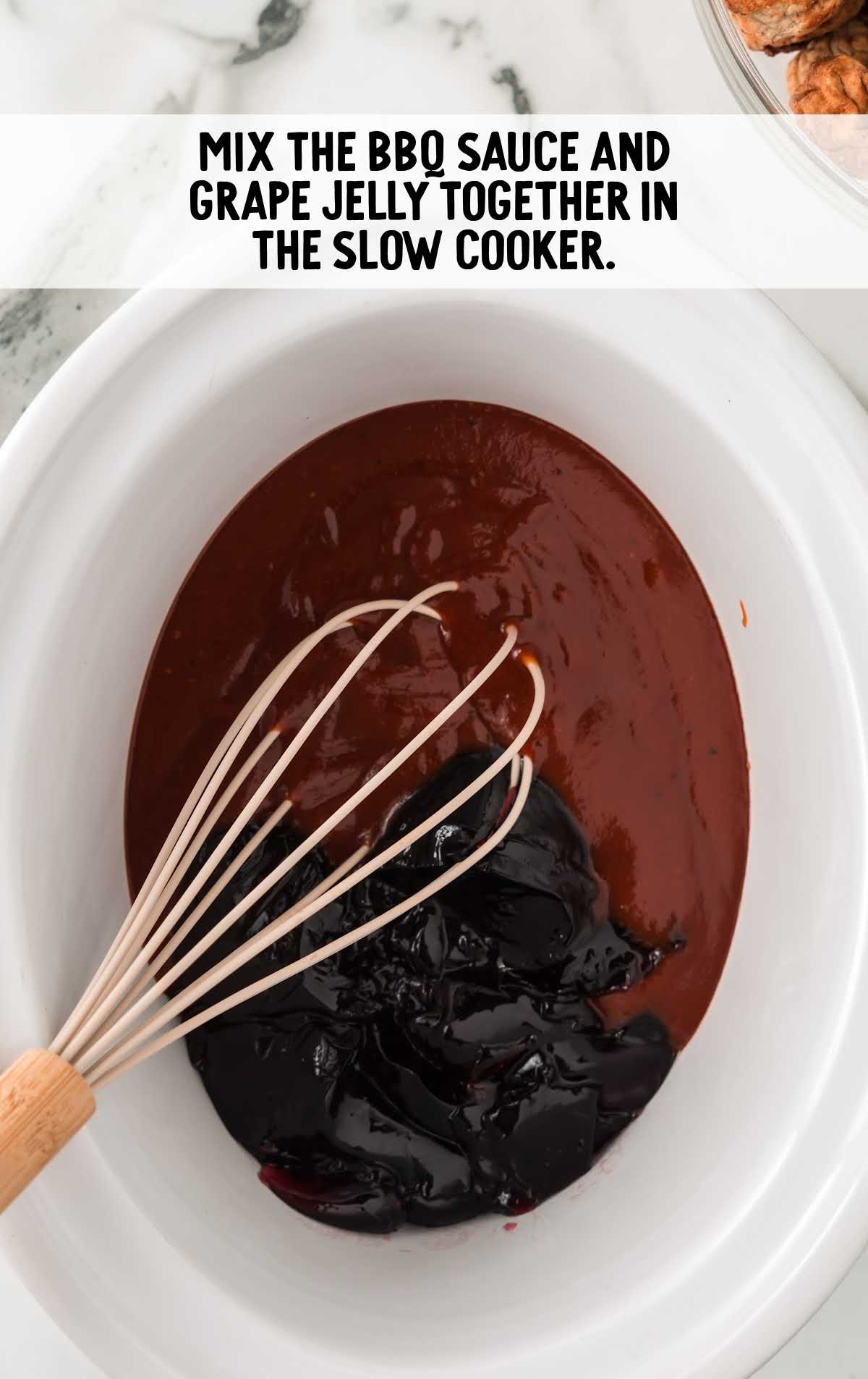 bbq sauce and grape jelly being whisked together in a crockpot