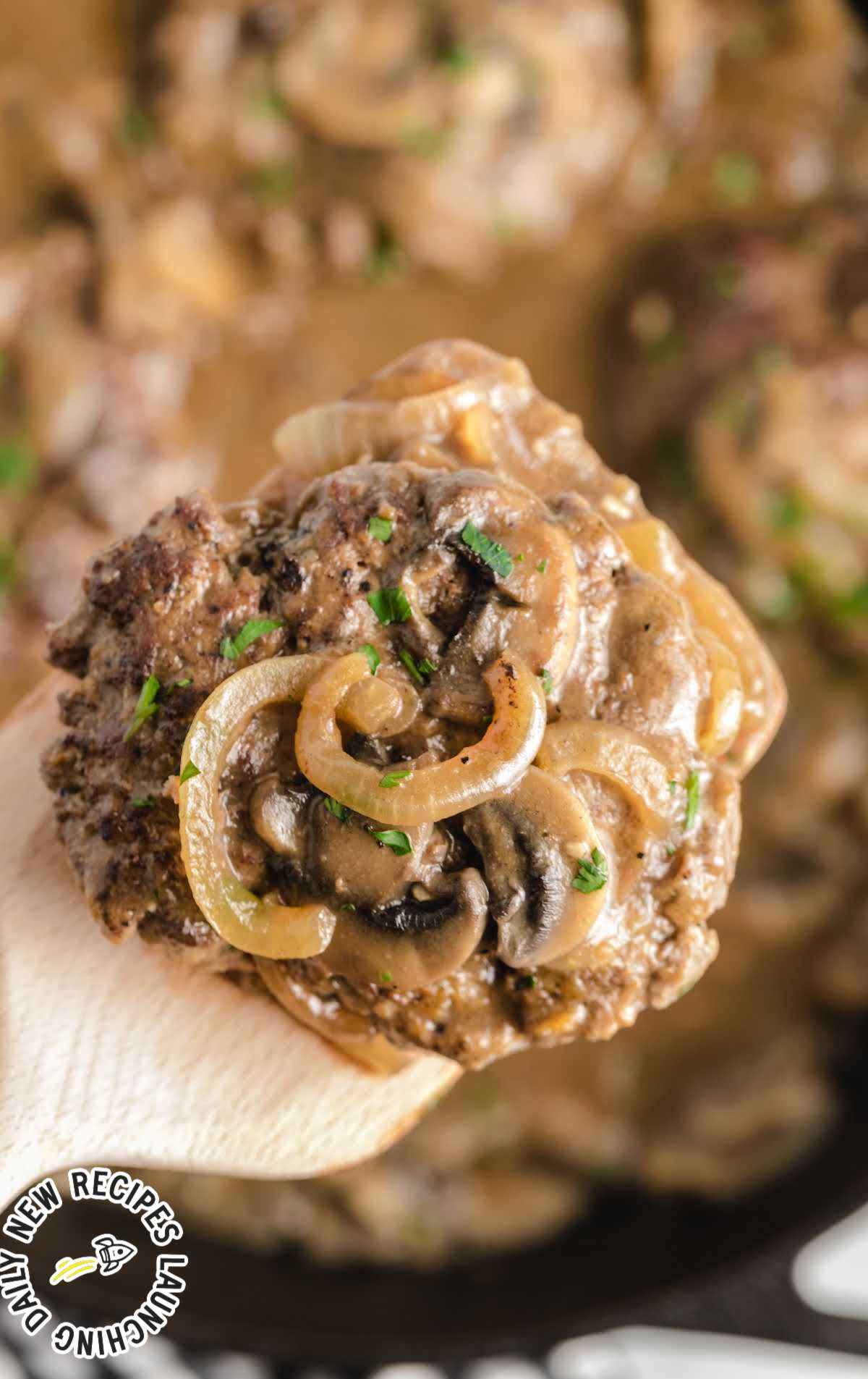 close up shot of Hamburger Steak garnished with parsley on a wooden spoon