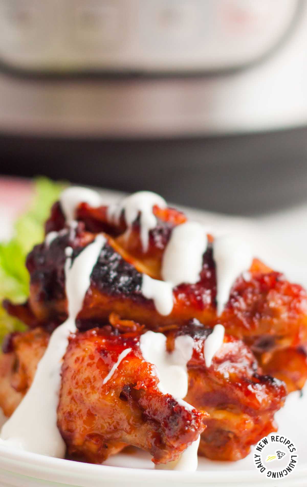 close up shot of a plate of Instant Pot Chicken Wings drizzled with blue cheese dressing