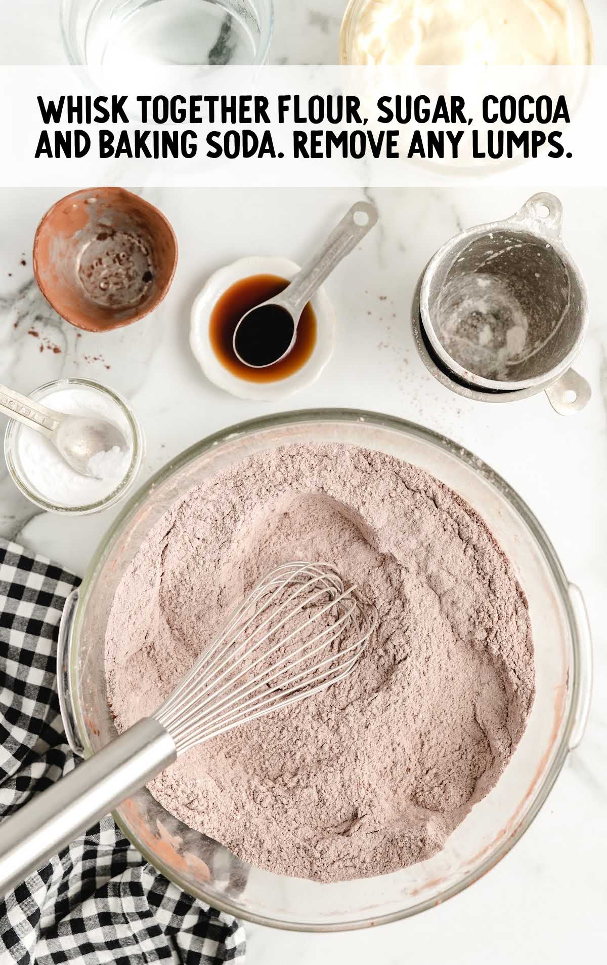 flour, sugar, cocoa, and baking soda whisked together in a bowl