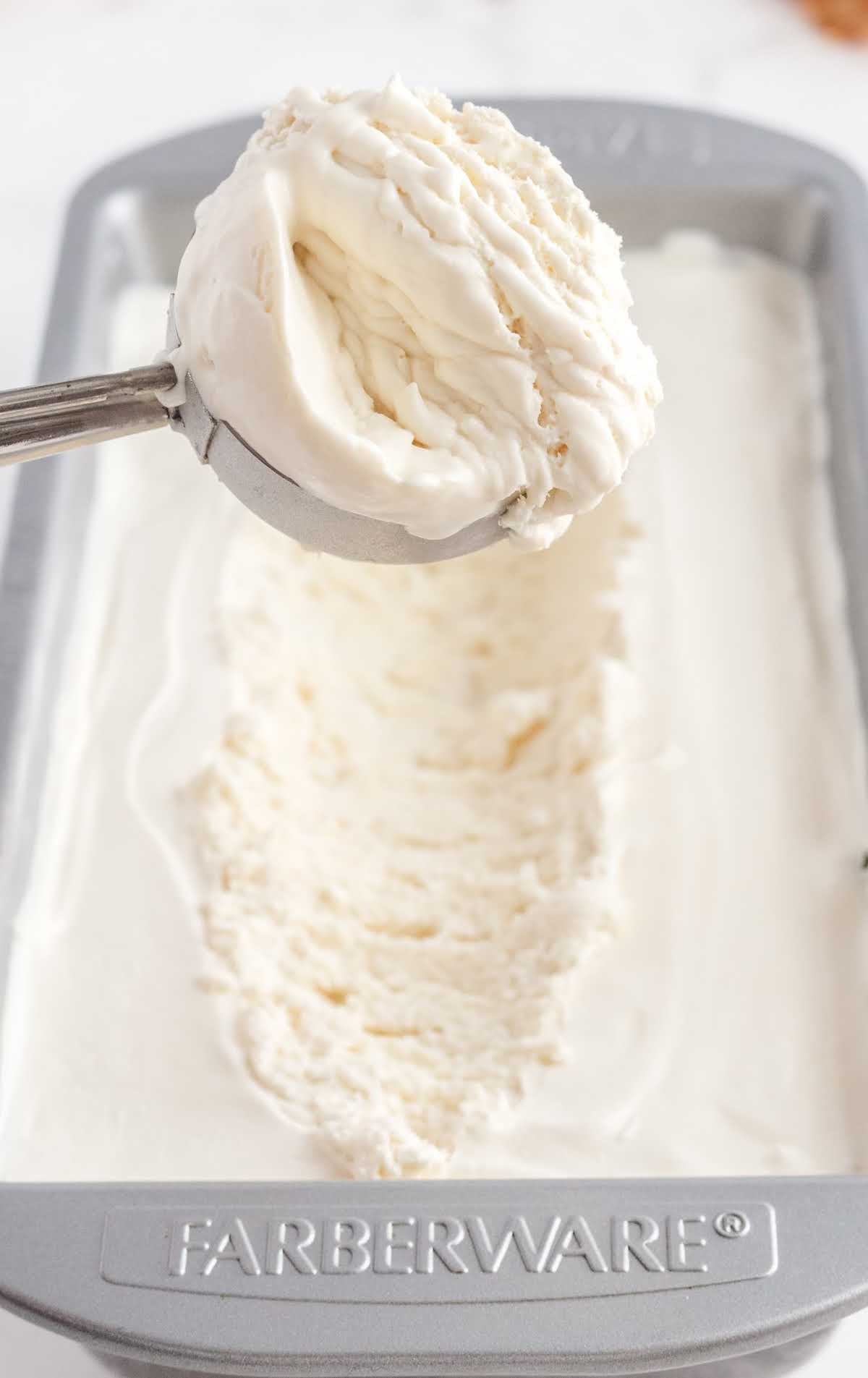 close up shot of a loaf pan of No-Churn Vanilla Ice Cream with a scoop of ice cream taken out