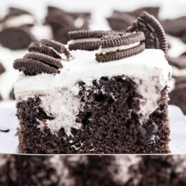 close up shot of a slice of Oreo Poke Cake garnished with pieces of Oreos on a spatula